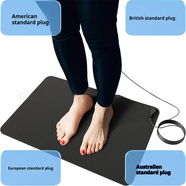 Person standing barefoot on a black rectangular grounding mat with a connected wire, used for earthing.
