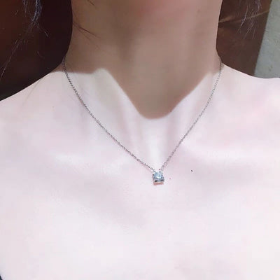Delicate silver-colored chain necklace with a single square-cut clear stone pendant in a four-prong setting on a woman's neck. - Image 8