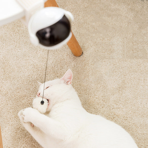 Pink automatic lifting cat toy with a black visor-like front, a clamp, and a white fluffy ball on a string.