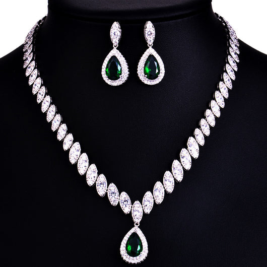 Silver-toned necklace and earring set with red teardrop stones and clear marquise-cut accents on a black display. - Image 6