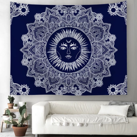 Blue traditional sun god tapestry with a white mandala design, hanging above a white sofa in a living room.