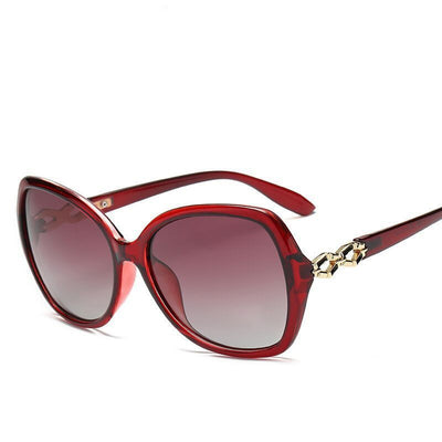 Women's purple oversized polarized sunglasses with gradient lenses and gold chain link detail on the temples.