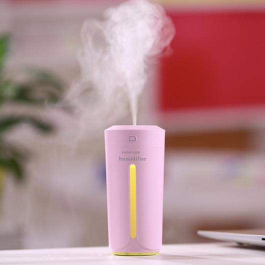 White mini USB ultrasonic humidifier with a green LED light strip, emitting mist, on a white surface. - Image 7