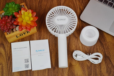 White ORICO FH1 handheld USB fan with charging dock, USB cable, and user manuals on a wooden desk. - Image 7
