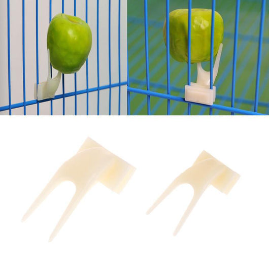 White plastic bird fruit fork clipped onto blue birdcage bars, designed to hold fruit or vegetables for pet birds. - Image 5