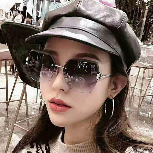 Woman wearing oversized hexagonal rimless sunglasses with gradient lenses and a black leather newsboy cap. - Image 3
