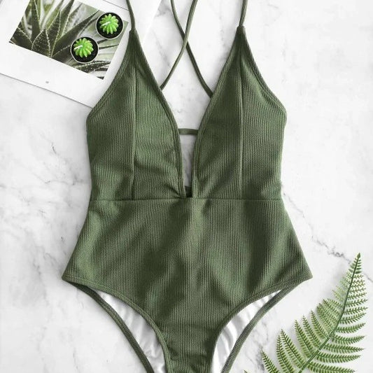 Olive green ribbed one-piece swimsuit with deep V-neck and criss-cross back straps, laid flat on marble.