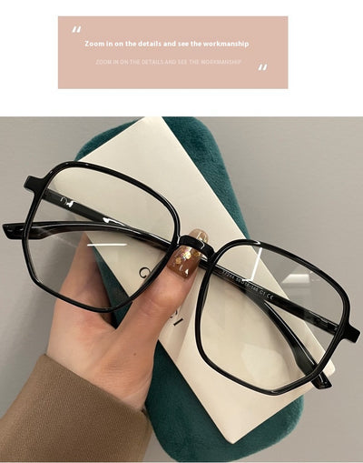 Mocha brown irregular frame glasses with clear lenses, held over a dark green velvet glasses case. - Image 17