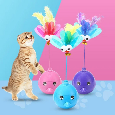 Purple electric tumbler cat toy with a blue bird-like top, pink feathers, googly eyes, and small bells.