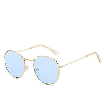 Round gold-framed sunglasses with pink tinted lenses, featuring clear temple tips.