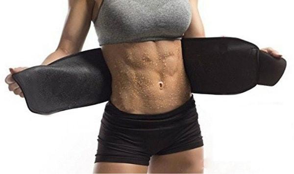 Person wearing a black neoprene abdominal waist trainer, with visible sweat on their toned midsection.