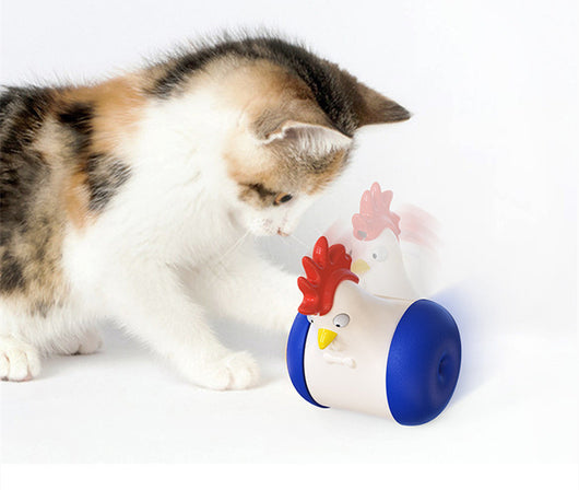 White and yellow chicken-shaped tumbler cat toy with a laser pointer, being played with by two orange tabby cats. - Image 10