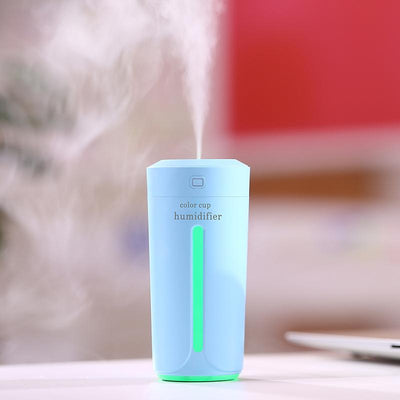 White mini USB ultrasonic humidifier with a green LED light strip, emitting mist, on a white surface. - Image 6