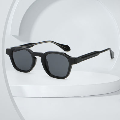 Classic fashion sunglasses with a black and tortoiseshell quadrilateral frame and dark green lenses, angled view.