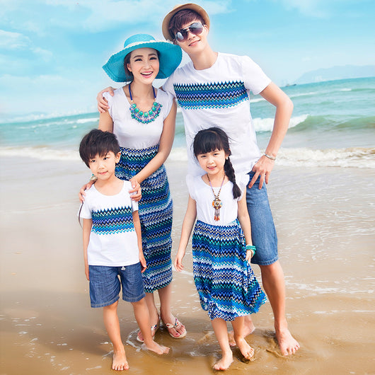 Family of four wearing matching white and blue striped outfits on a sunny beach, smiling at the camera. - Image 5