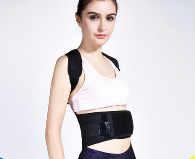 Woman wearing a black posture corrector with shoulder straps and a wide waist belt over a pink sports bra. - Image 3