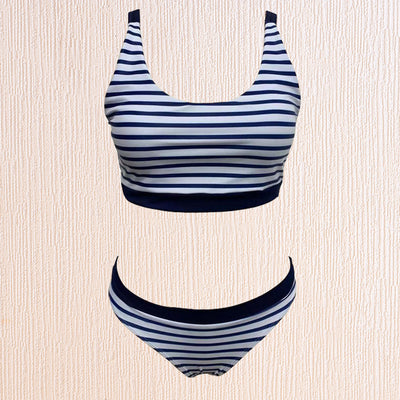 Woman smiling on a beach wearing a navy and white striped two-piece bikini with a racerback top. - Image 5