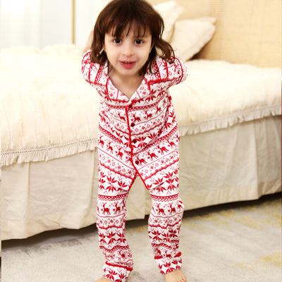 Woman wearing a red and white fair isle reindeer print short-sleeve pajama set with long pants in a bedroom. - Image 5