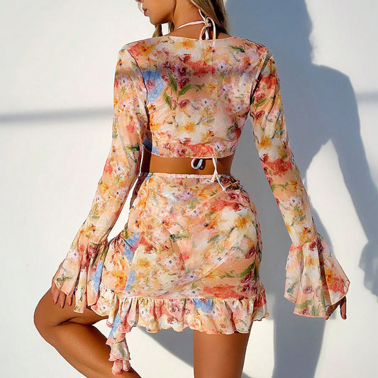 Four-piece women's beachwear set with a peach, blue, and green floral print. Includes a triangle bikini, long-sleeve tie-front cover-up, and ruched mini skirt. - Image 2