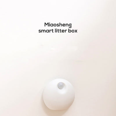 White spherical smart pet deodorizer with a sensor, designed for litter basins, shown against a light gray background with green leaves. - Image 10