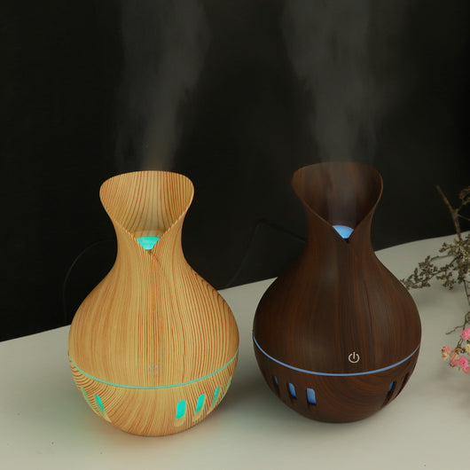 Dark brown wood grain mini USB humidifier with a vase-like shape and a green LED light band and slots.