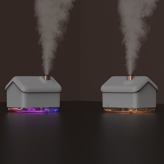 Pink and white house-shaped humidifier and essential oil diffuser with a clear base and a white power cord.