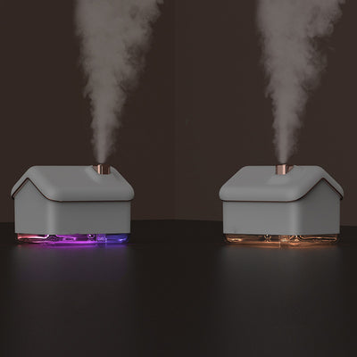 Pink and white house-shaped humidifier and essential oil diffuser with a clear base and a white power cord.
