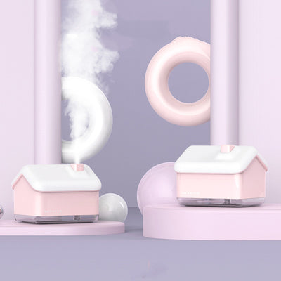Pink and white house-shaped humidifier and essential oil diffuser with a clear base and a white power cord. - Image 4