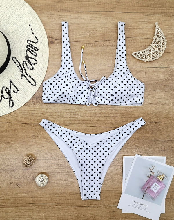 Red polka dot print two-piece swimsuit with a lace-up front bikini top and high-cut bottoms on a wooden surface. - Image 4