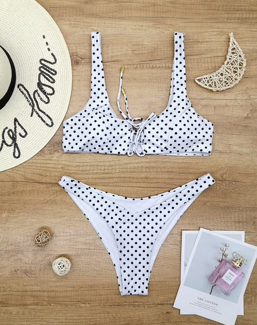 Red polka dot print two-piece swimsuit with a lace-up front bikini top and high-cut bottoms on a wooden surface. - Image 4