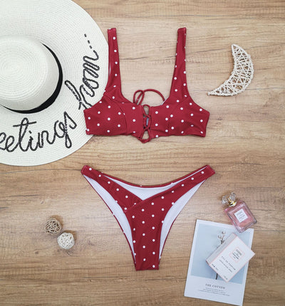 Red polka dot print two-piece swimsuit with a lace-up front bikini top and high-cut bottoms on a wooden surface. - Image 6