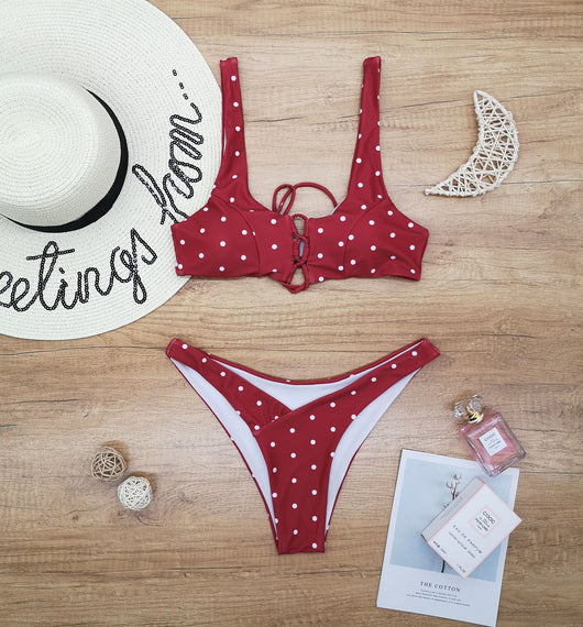 Red polka dot print two-piece swimsuit with a lace-up front bikini top and high-cut bottoms on a wooden surface. - Image 6