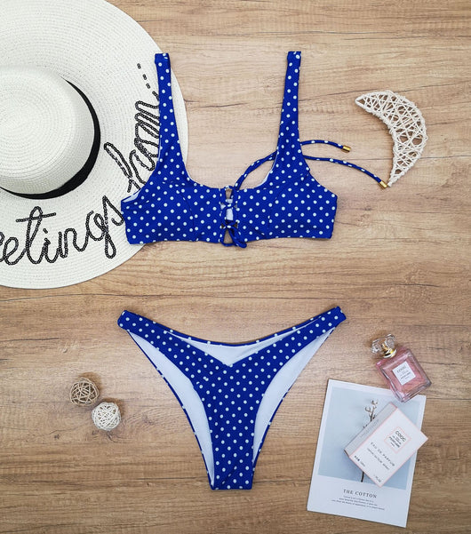 Red polka dot print two-piece swimsuit with a lace-up front bikini top and high-cut bottoms on a wooden surface. - Image 5