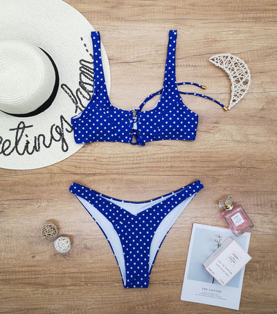 Red polka dot print two-piece swimsuit with a lace-up front bikini top and high-cut bottoms on a wooden surface. - Image 10