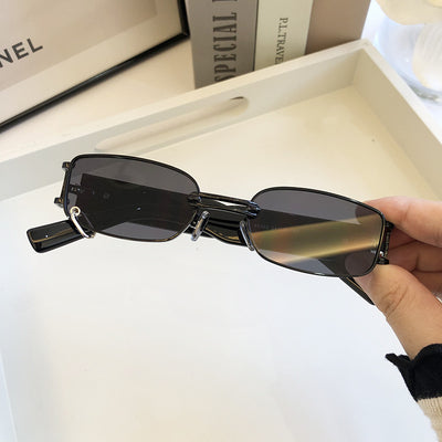 Black rectangular sunglasses with dark lenses and a thin metal frame, held by a hand against a light background. - Image 4