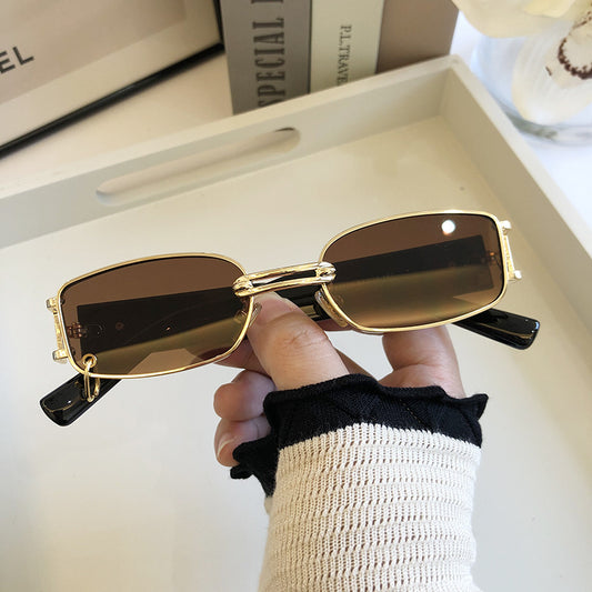 Black rectangular sunglasses with dark lenses and a thin metal frame, held by a hand against a light background. - Image 2