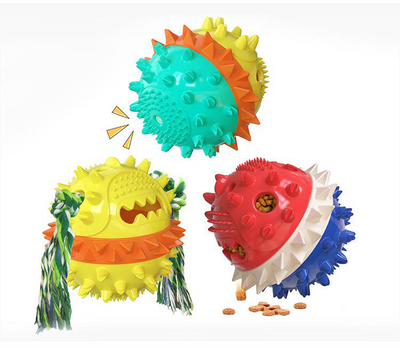 Yellow spiky dog toy with orange band and green rope, designed for chewing and treat dispensing, next to a yawning puppy. - Image 10