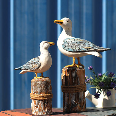 Set of two carved wooden seagull figurines on distressed posts with rope, featuring white, blue, and orange colors. - Image 7