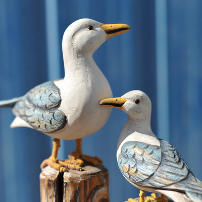 Set of two carved wooden seagull figurines on distressed posts with rope, featuring white, blue, and orange colors. - Image 6