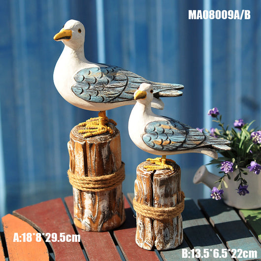 Set of two carved wooden seagull figurines on distressed posts with rope, featuring white, blue, and orange colors. - Image 3