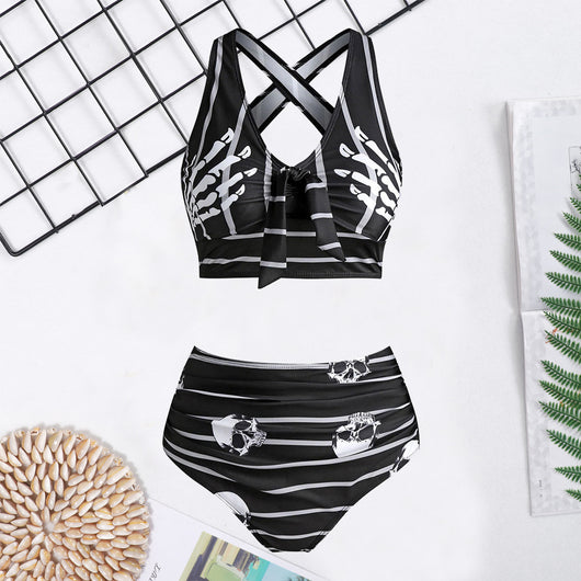 Woman in a black two-piece swimsuit with white skull and bone prints, featuring a high-waisted bottom and a bow-front top. - Image 11