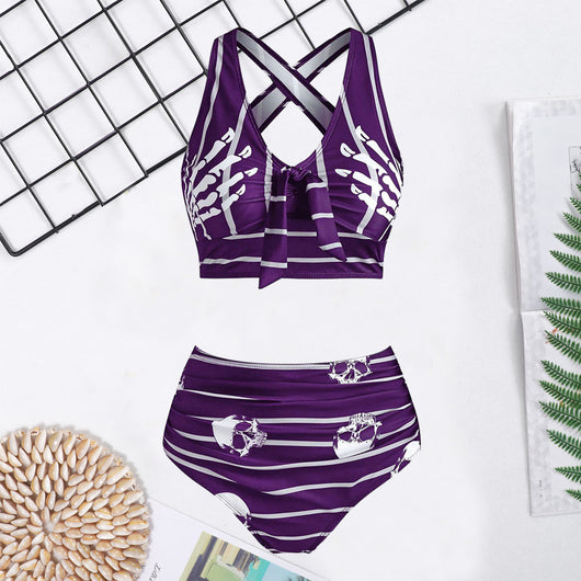 Woman in a black two-piece swimsuit with white skull and bone prints, featuring a high-waisted bottom and a bow-front top. - Image 4