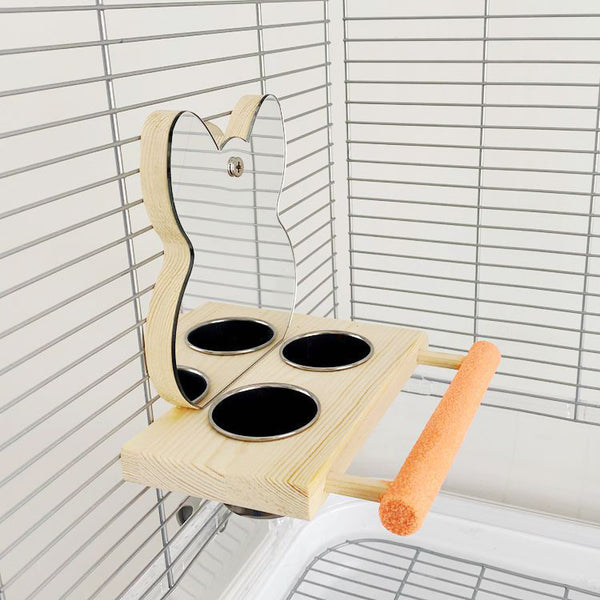 Parrot puzzle bird toy with a wooden stand, mirror, two stainless steel food cups, and an orange perching bar.