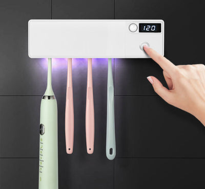White toothbrush disinfector with UV light, USB cable, alcohol prep pad, and mounting strips on a light blue background. - Image 2