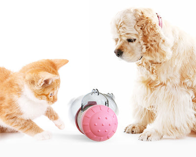 Pink and white bear-shaped pet treat dispenser toy filled with kibble, with a kitten and dog in the background. - Image 2