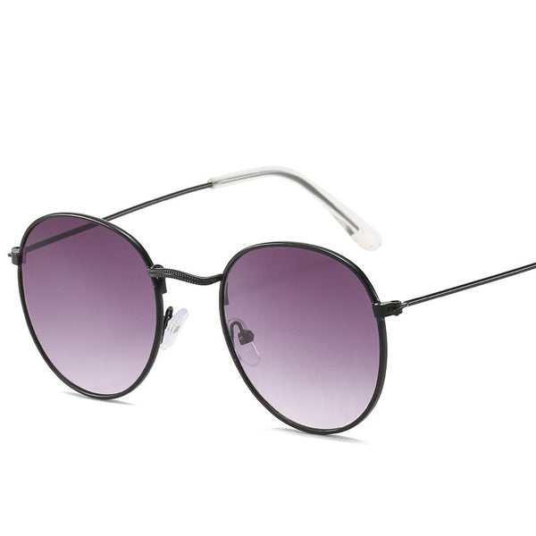 Retro oval sunglasses with pink lenses and a gold metal frame, featuring clear temple tips.