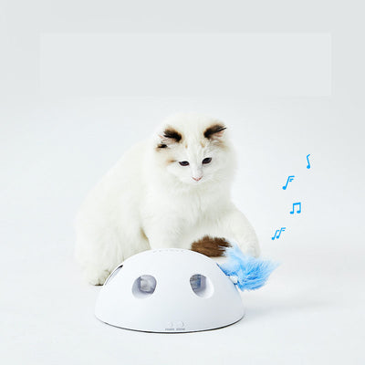 White cat playing with a white dome-shaped electric cat toy, featuring blue feathers visible through openings. - Image 7