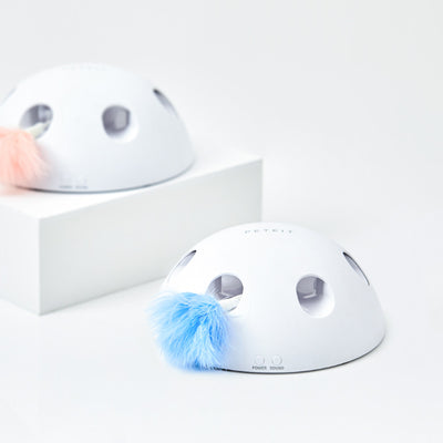 White cat playing with a white dome-shaped electric cat toy, featuring blue feathers visible through openings. - Image 2