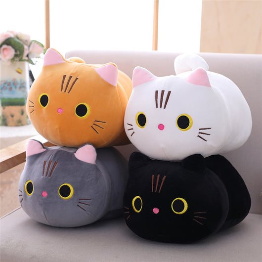 Cute orange cat plush doll with pink ears, black eyes, and embroidered whiskers, resting on a white book.