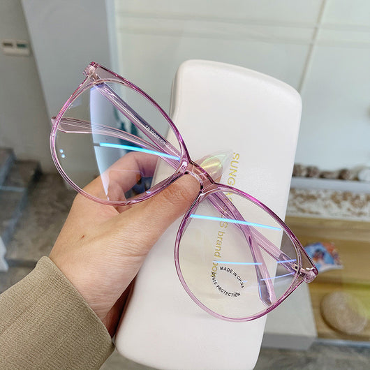 Transparent pink round-face anti-blue light glasses with clear lenses, held against a white glasses case. - Image 2